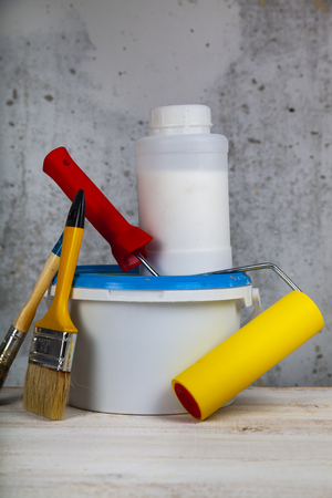Paint can,roller and brush on the table. Items for home or office renovation against a gray wall.の写真素材
