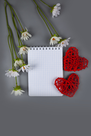 Two hearts, daisies and card on a gray background. Congratulations on Valentine's Day or Mother's Dayの写真素材