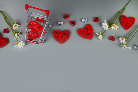 Hearts, flowers and shopping cart on a grey background. Shopping for the holiday.の写真素材