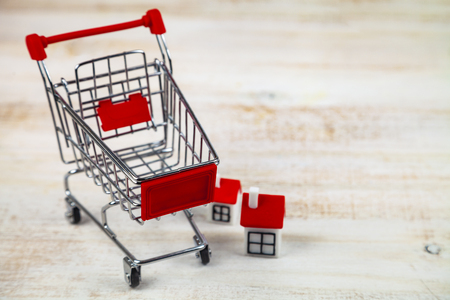 Shopping cart and houses. Concept: buying, selling and renting real estate.の写真素材