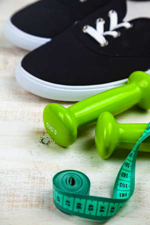 Sneakers, dumbbells and measuring tape on a wooden background. Concept of a healthy lifestyle and sport.の写真素材