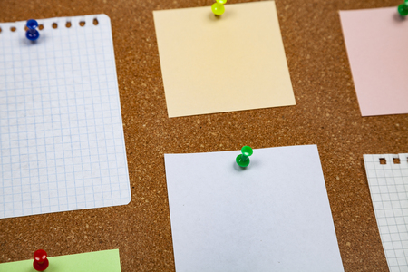 Corkboard with notes. Colored paper on corkboard.の写真素材