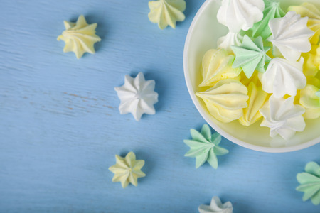 Meringue in white bowl on a blue  wooden background, top view. Delicious dessert. Colorful handmade meringue .の写真素材