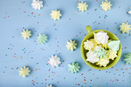 Meringue in a green cup on a blue  wooden background, top view. Delicious dessert. Colorful handmade meringue .の写真素材