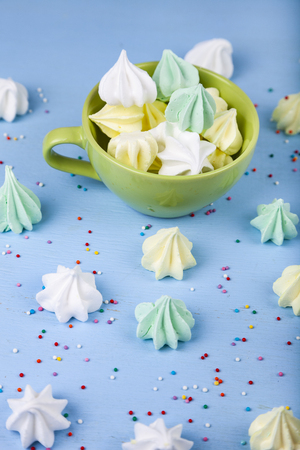 Meringue in white bowl on a blue  wooden background. Delicious dessert. Colorful handmade meringueの写真素材