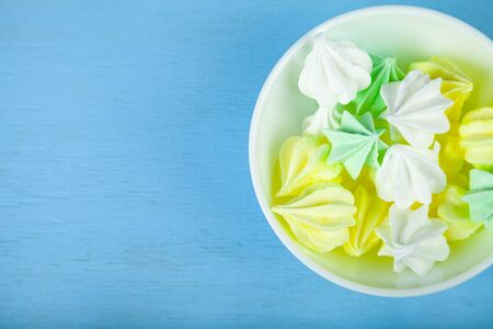 Meringue in a white bowl on a blue  wooden background. Delicious dessert. Colorful handmade meringue.の写真素材