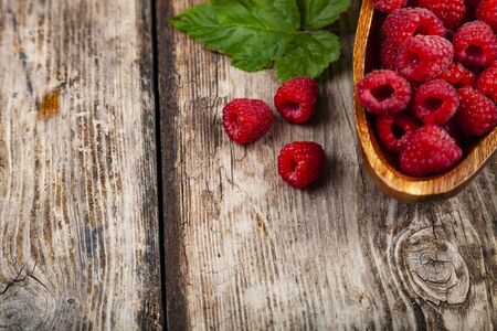 Ripe raspberries in a bowl on an old wooden table. Delicious berries.の写真素材