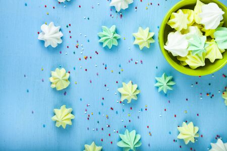 Meringue in a green cup on a blue  wooden background, top view. Delicious dessert. Colorful handmade meringue.の写真素材