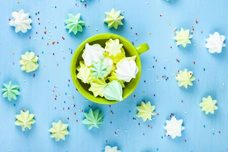 Meringue in a green cup on a blue  wooden background, top view. Delicious dessert. Colorful handmade meringue.の写真素材