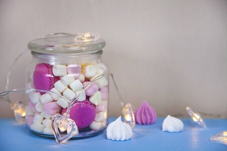 Marshmallow in a glass jar and a garland of hearts. Delicious dessert.