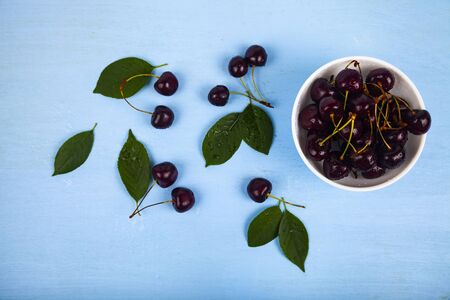 Ripe sweet cherry in a white bowl on a wooden table, top view. Delicious berries.の写真素材