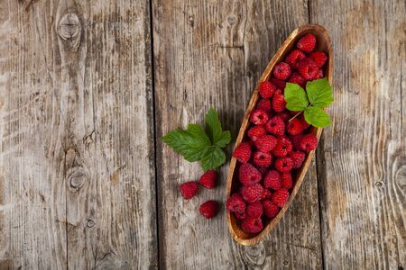Ripe raspberries in a bowl on an old wooden table. Delicious berries.