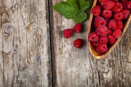 Ripe raspberries in a bowl on an old wooden table. Delicious berries.の写真素材