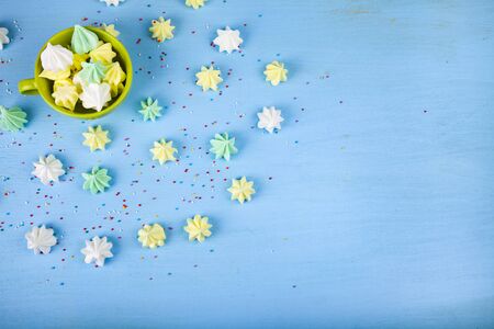 Meringue in a green cup on a blue  wooden background, top view. Delicious dessert. Colorful handmade meringue.の写真素材
