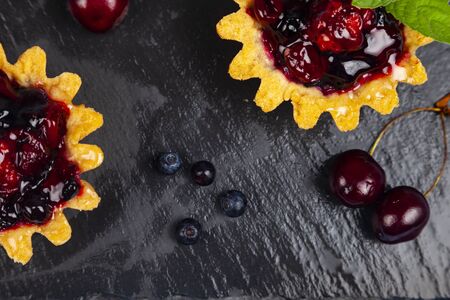Small berry cake, sweet cherry, blueberry and mint on a black slate tray. Delicious dessert.の写真素材