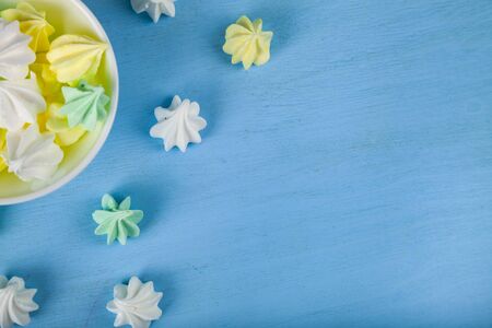 Meringue in a white bowl on a blue  wooden background, top view. Delicious dessert. Colorful handmade meringue.の写真素材
