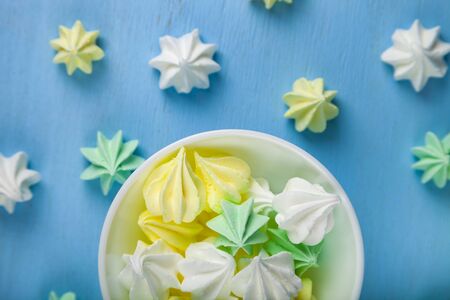 Meringue in a white bowl on a blue  wooden background, top view. Delicious dessert. Colorful handmade meringue.の写真素材