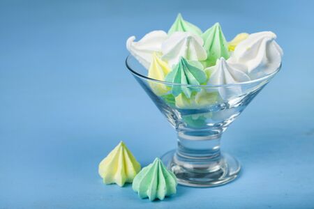 Meringue in a transparent bowl on a blue  wooden background. Delicious dessert. Colorful handmade...