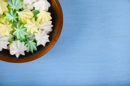 Meringue in a bowl on a blue  wooden background, top view. Delicious dessert. Colorful handmade...