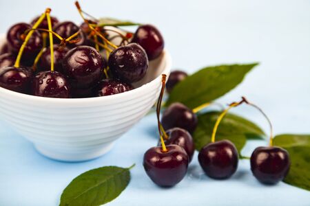 Ripe sweet cherry in a white bowl on a wooden table. Delicious berries.の写真素材