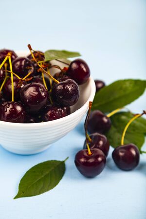 Ripe sweet cherry in a white bowl on a wooden table. Delicious berries.の写真素材