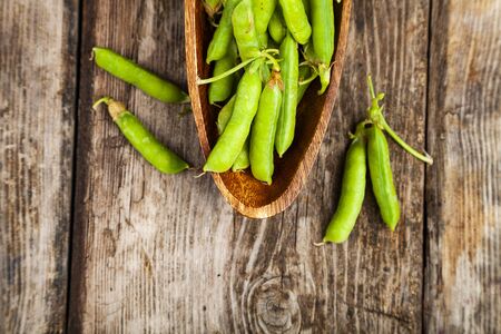 Green peas in a wooden bowl. Pea pods on a wooden background.の写真素材