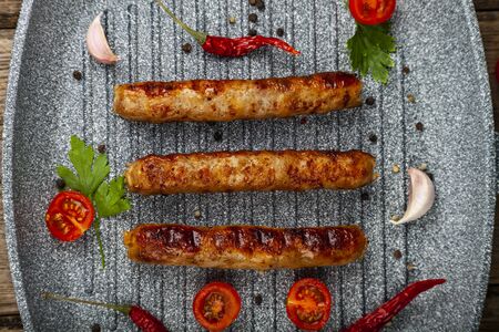 Kupaty in a frying pan, vegetables and spices. Sausages grill. Tasty food.の写真素材