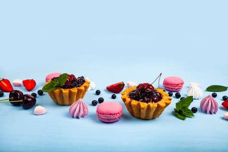 Small berry cake and ripe berries on a blue wooden background. Delicious dessert.の写真素材