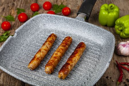 Kupaty in a frying pan, vegetables and spices. Sausages grill. Tasty food.の写真素材
