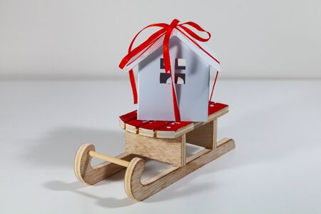 House with a gift ribbon on a sleigh. Winter sale of real estate. Concept: buying, selling and...