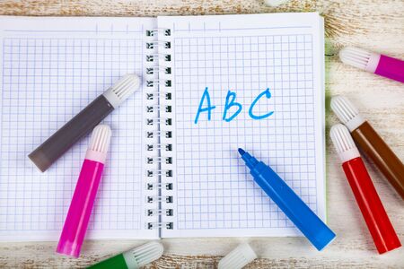 Back to school. Colored felt-tip pens and notebook on blue wooden background.の写真素材