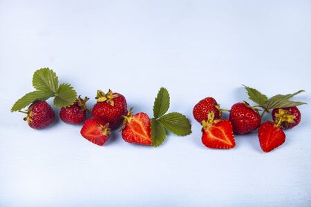 Ripe strawberries and leaves on a blue background. Still life with berries.の写真素材