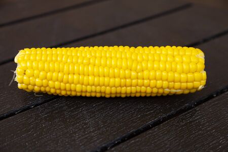 Boiled corn on a brown wooden table.