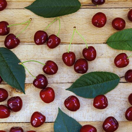 Ripe cherries and leaves on a wooden background. Tasty berries. Still life.