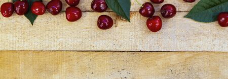 Ripe cherries and leaves on a wooden background. Tasty berries. Still life.Place for your text.の写真素材