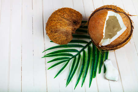 Coconut and palm leaves on a white wooden background.