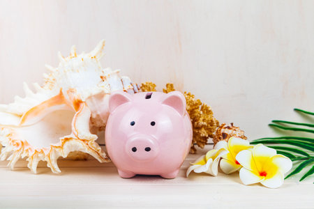 Pig piggy bank, palm leaf and seashells on a wooden background. Concept: saving for vacation.の写真素材