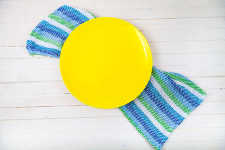 Empty yellow plate and towel on a wooden background.の写真素材