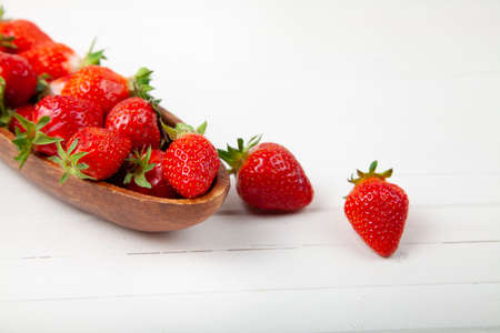 Ripe strawberries in a wooden plate on a wooden background. Still life with delicious berries.の写真素材