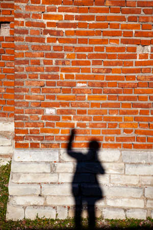 Shadow of a man on a brick wall background.の写真素材