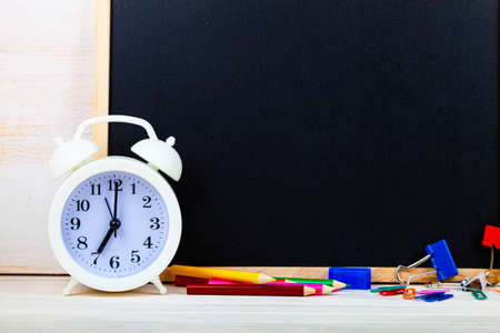 Alarm clock and chalk board on a wooden table. Back to school. Stationery.の写真素材