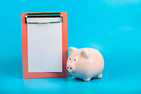Pig piggy bank and paper on a blue background.の写真素材