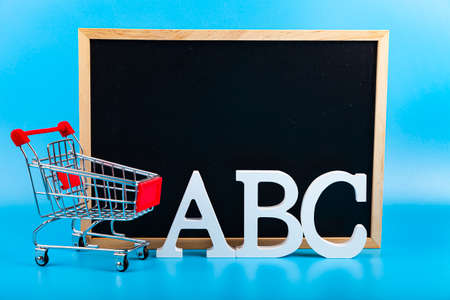 ABC letters and shopping cart on a blue background. Shopping for school. Back to school.