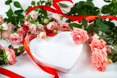 Bouquet of pink roses and a plate in the form of a heart on a light background. Greeting card.の写真素材