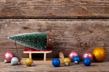 Christmas tree on sledges and balls on a wooden background. Festive postcard.の写真素材