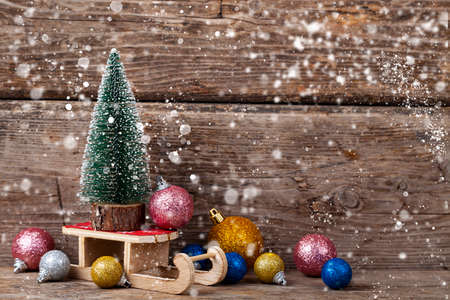 Christmas tree on sledges and balls on a wooden background. Festive postcard.