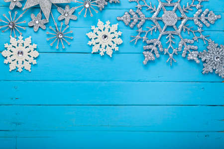 White and silver Christmas snowflakes on a blue wooden background. Christmas card. Place for your...