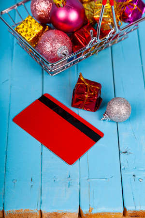 Shopping basket with Christmas gifts, decor and credit card on a blue wooden background. Christmas sale.の写真素材
