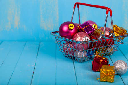 Shopping basket with Christmas gifts, decor and balls on a blue wooden background. Christmas sale.の写真素材