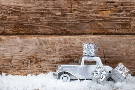 Car is carrying Christmas presents. Christmas background with snow, Christmas trees, balls and auto.の写真素材